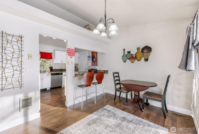 dining room featuring dark wood-style floors, baseboards, visible vents, and a notable chandelier