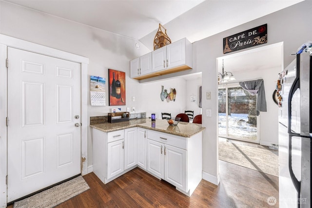 kitchen featuring lofted ceiling, dark wood-type flooring, freestanding refrigerator, and white cabinets