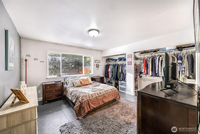 bedroom with concrete floors and multiple closets