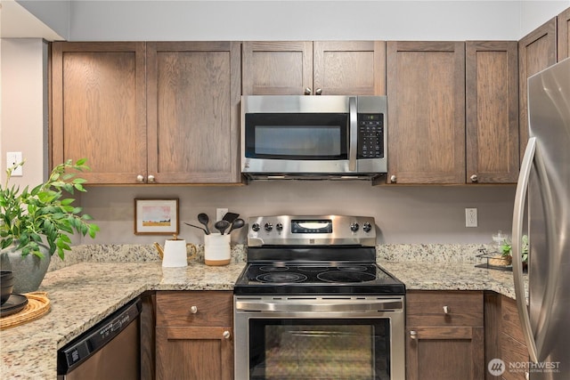 kitchen with light stone countertops and appliances with stainless steel finishes