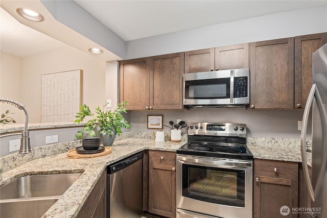 kitchen featuring stainless steel appliances, sink, and light stone counters