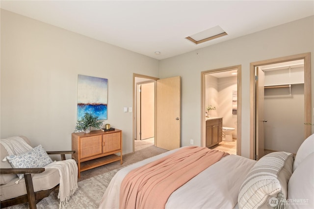 carpeted bedroom with a walk in closet and ensuite bathroom