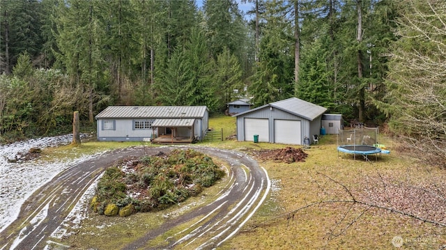 view of front facade with a garage, metal roof, a trampoline, and an outdoor structure