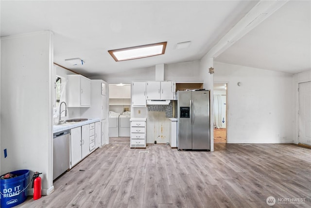 kitchen with white cabinets, appliances with stainless steel finishes, light countertops, separate washer and dryer, and a sink