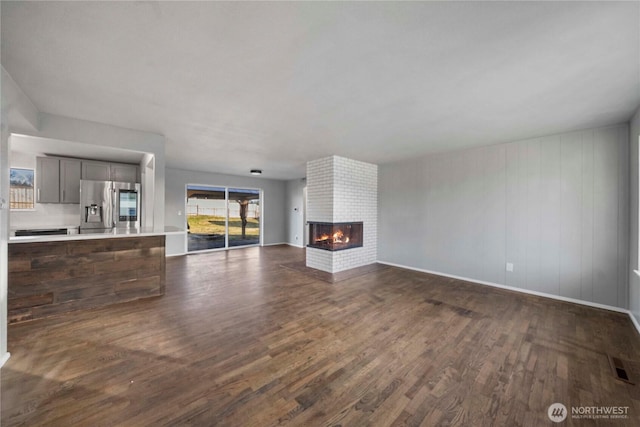 unfurnished living room with dark hardwood / wood-style floors and a brick fireplace