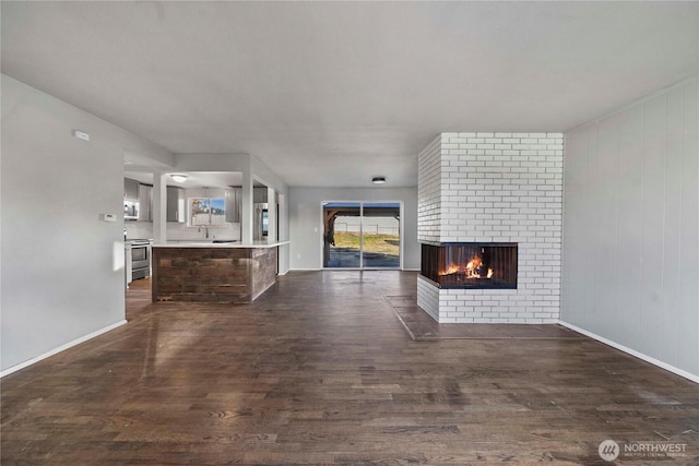 unfurnished living room with dark hardwood / wood-style floors and a brick fireplace