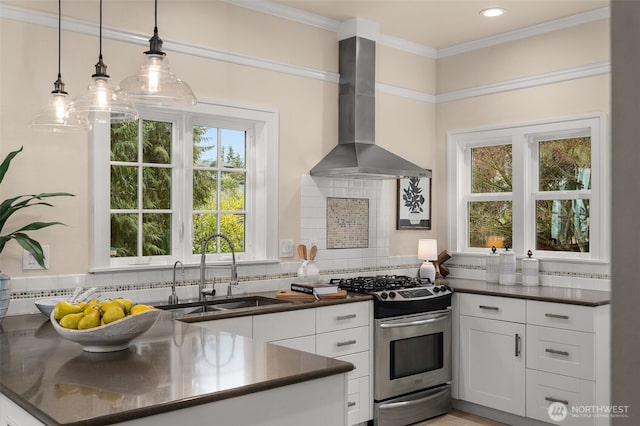 kitchen featuring white cabinets, wall chimney range hood, decorative light fixtures, gas stove, and sink