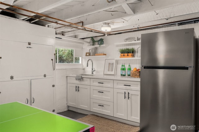 kitchen with sink, white cabinetry, and stainless steel fridge