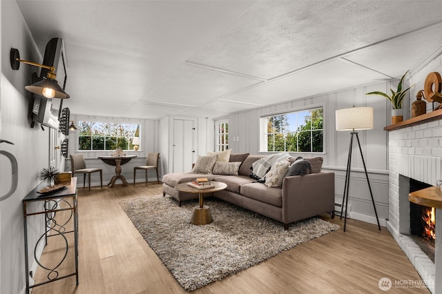 living room featuring wood-type flooring, a textured ceiling, and a fireplace