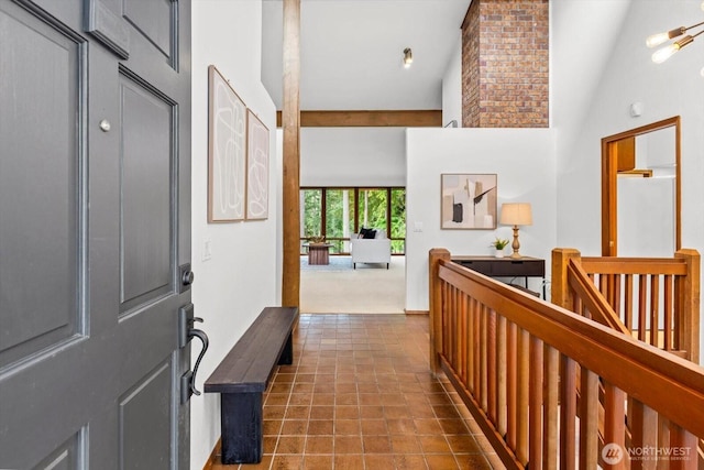 corridor with an upstairs landing, high vaulted ceiling, and dark tile patterned floors