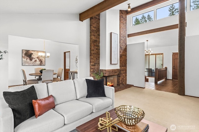 living area with beamed ceiling, high vaulted ceiling, carpet, an inviting chandelier, and a brick fireplace