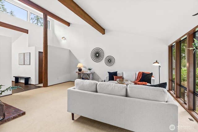 carpeted living room featuring vaulted ceiling with beams, a healthy amount of sunlight, and visible vents