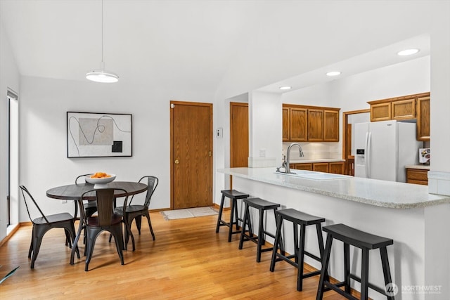 kitchen featuring light countertops, white refrigerator with ice dispenser, and light wood finished floors