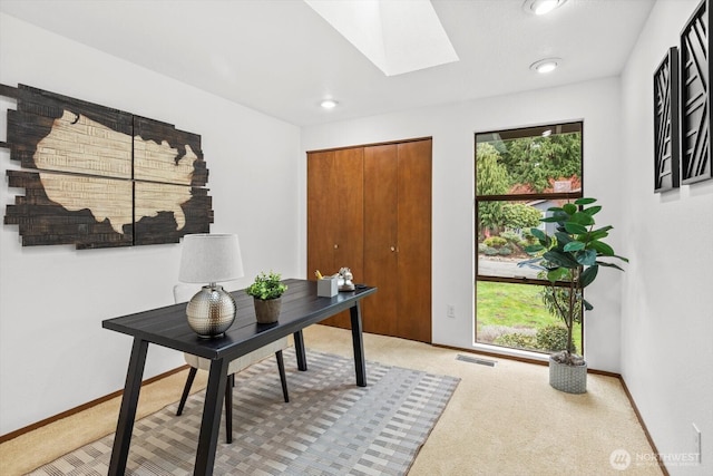 office space with visible vents, baseboards, light colored carpet, and a skylight