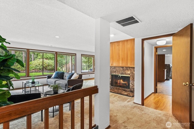 living area with visible vents, light carpet, light wood-style flooring, a textured ceiling, and a fireplace