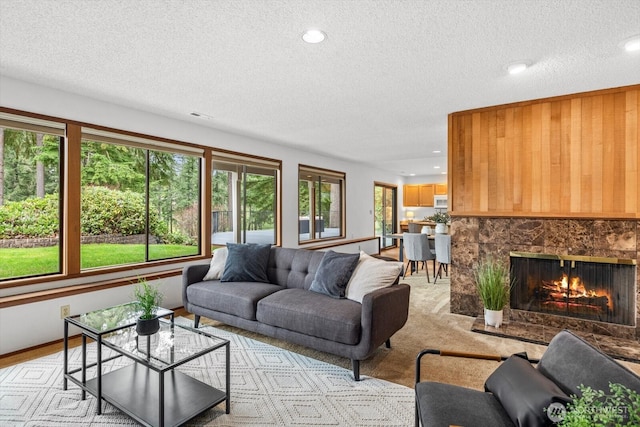 living area featuring a high end fireplace, recessed lighting, a textured ceiling, and light carpet