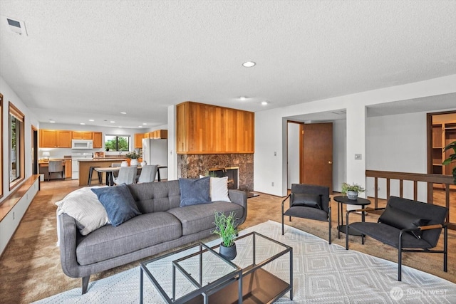 living area with a high end fireplace, visible vents, recessed lighting, and a textured ceiling