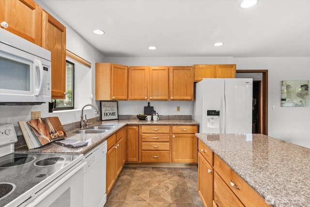 kitchen with light stone countertops, recessed lighting, brown cabinetry, white appliances, and a sink