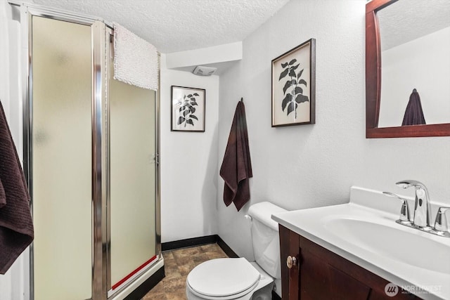 bathroom with a shower stall, a textured ceiling, vanity, and toilet