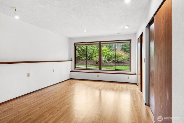 empty room featuring wood finished floors, baseboards, and a textured ceiling