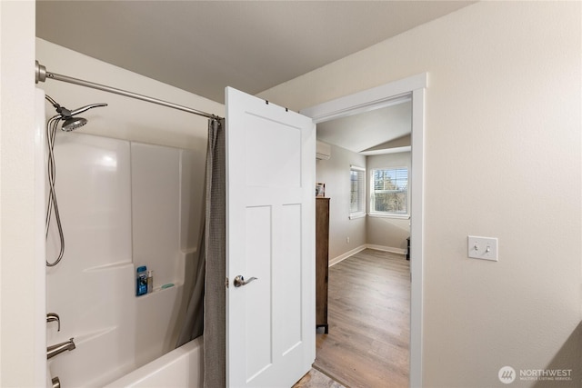 bathroom with hardwood / wood-style flooring, a wall mounted AC, and shower / tub combo