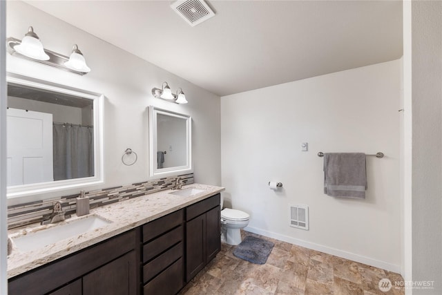 bathroom featuring vanity, backsplash, and toilet