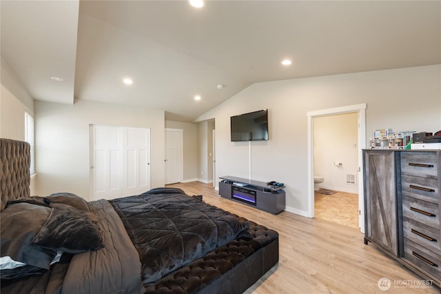 bedroom featuring lofted ceiling, connected bathroom, light hardwood / wood-style floors, and a closet