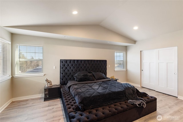 bedroom featuring multiple windows, lofted ceiling, and light wood-type flooring