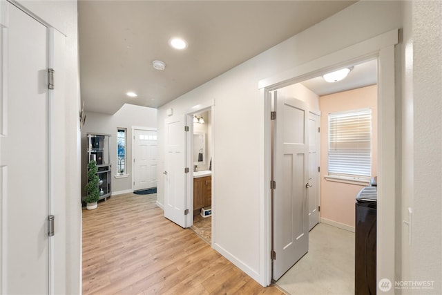 corridor featuring washer / clothes dryer and light wood-type flooring