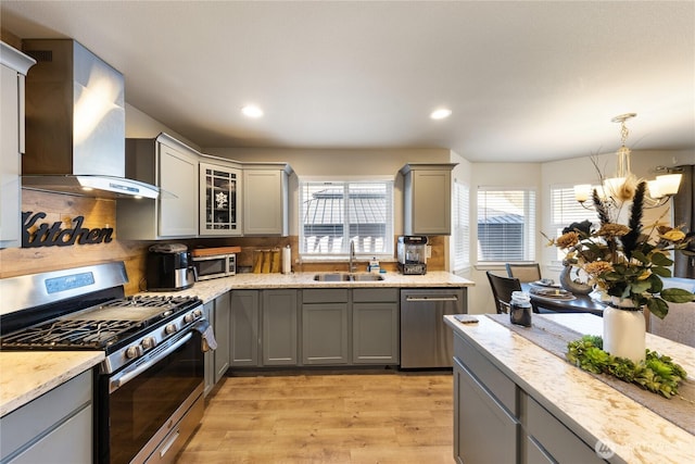 kitchen with wall chimney exhaust hood, appliances with stainless steel finishes, sink, and gray cabinetry