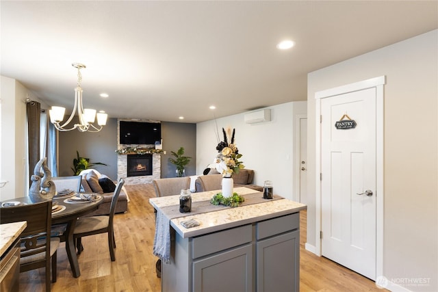 kitchen with an AC wall unit, pendant lighting, gray cabinetry, a center island, and light hardwood / wood-style floors