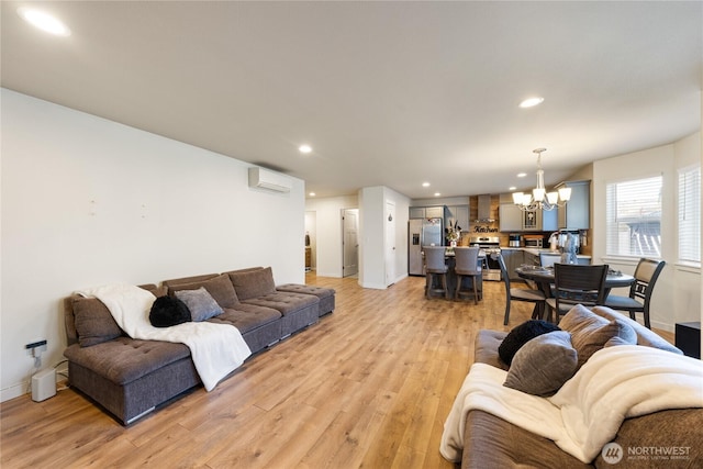 living room with an inviting chandelier, a wall unit AC, and light hardwood / wood-style flooring