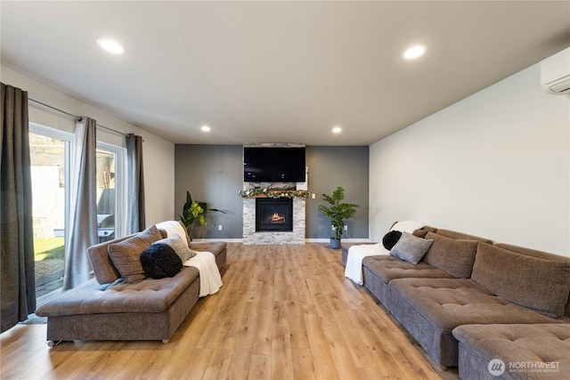 living room with light hardwood / wood-style flooring, a wall mounted air conditioner, and a fireplace