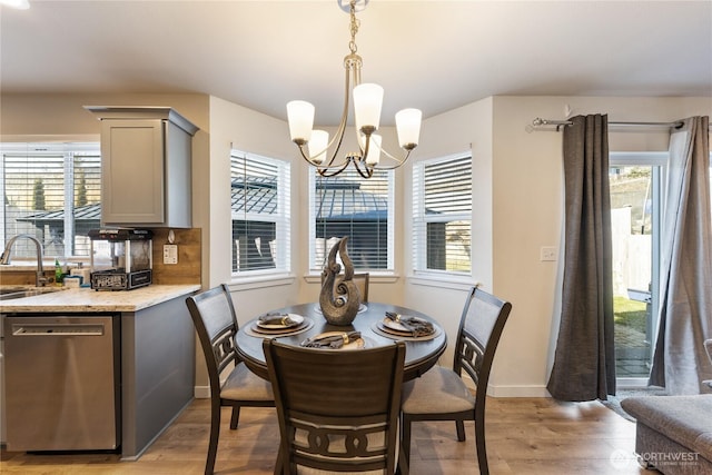 dining space featuring an inviting chandelier, a healthy amount of sunlight, sink, and light wood-type flooring