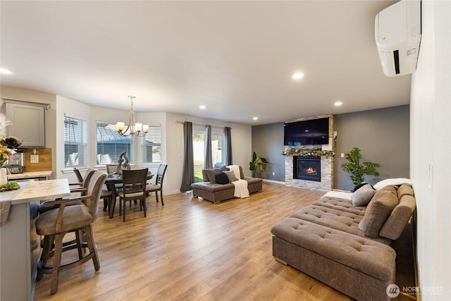 living room featuring a fireplace, light hardwood / wood-style floors, a wall unit AC, and a chandelier