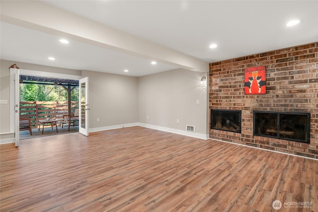 unfurnished living room featuring beamed ceiling, hardwood / wood-style floors, and a fireplace