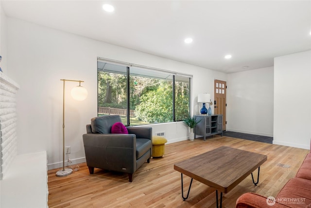 living room featuring a brick fireplace and light wood-type flooring