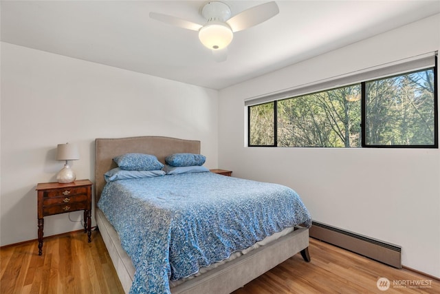 bedroom with a baseboard radiator, wood-type flooring, and ceiling fan