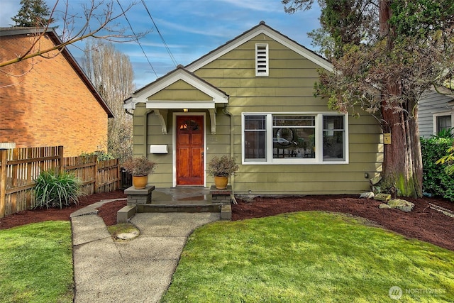 bungalow with a front lawn and fence