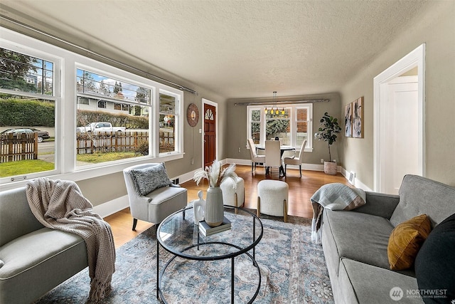 living room featuring a textured ceiling, baseboards, and wood finished floors