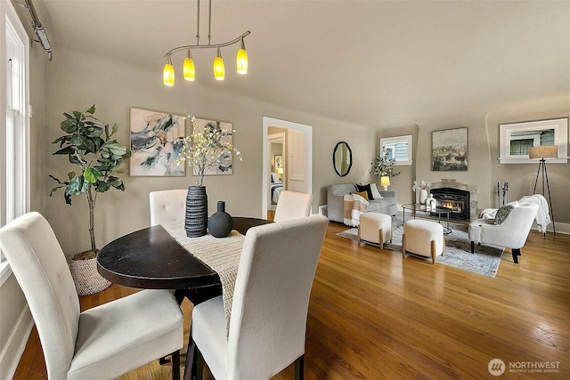 dining area with a glass covered fireplace and wood finished floors