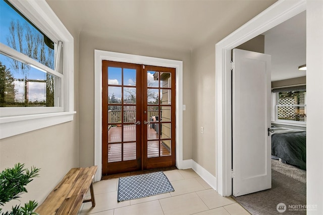 doorway with french doors, plenty of natural light, baseboards, and light tile patterned floors