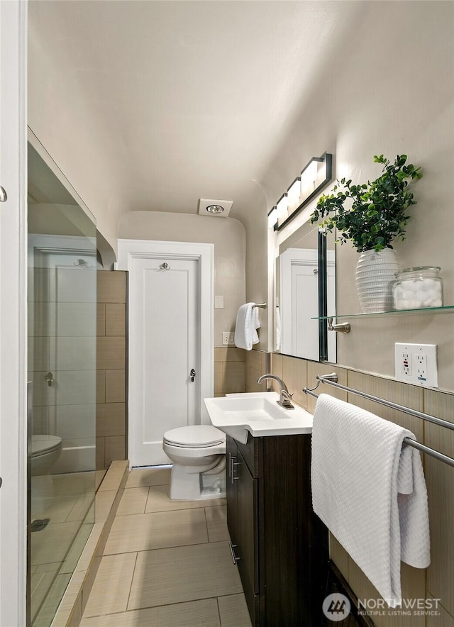 bathroom featuring tasteful backsplash, toilet, vanity, tile patterned flooring, and tiled shower