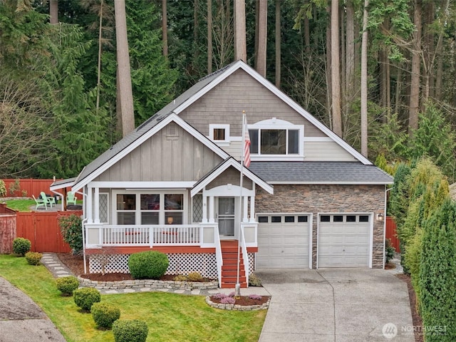 view of front facade featuring board and batten siding, concrete driveway, covered porch, a garage, and stone siding