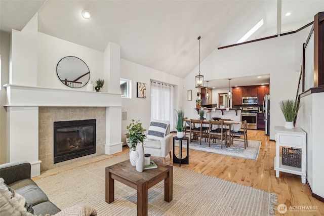 living room with high vaulted ceiling, light wood-style floors, recessed lighting, and a fireplace