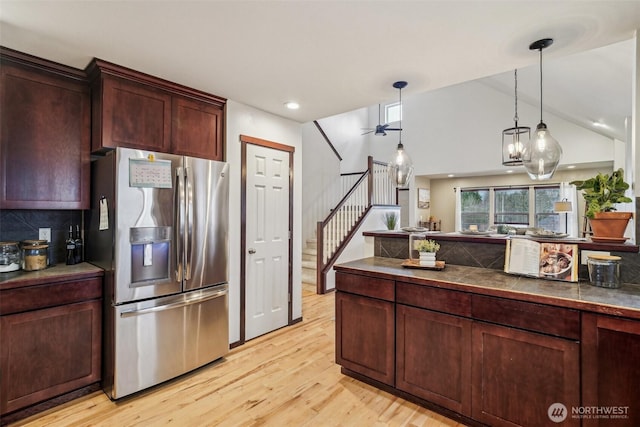 kitchen with stainless steel fridge with ice dispenser, vaulted ceiling, decorative backsplash, light wood-style floors, and hanging light fixtures