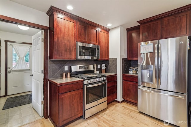 kitchen featuring light wood-style flooring, recessed lighting, stainless steel appliances, reddish brown cabinets, and decorative backsplash