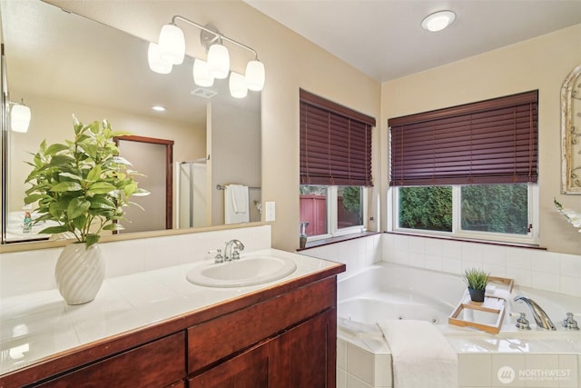 full bathroom featuring a tub with jets, vanity, and visible vents