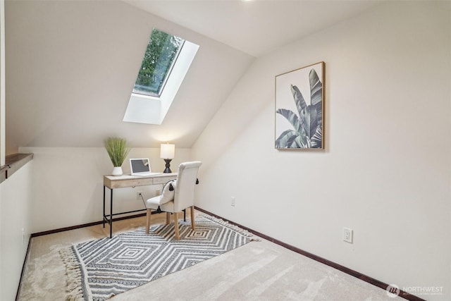 carpeted home office with baseboards and vaulted ceiling with skylight