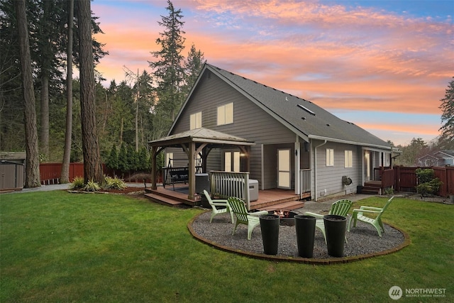 rear view of property with a lawn, fence, a gazebo, an outdoor fire pit, and a wooden deck